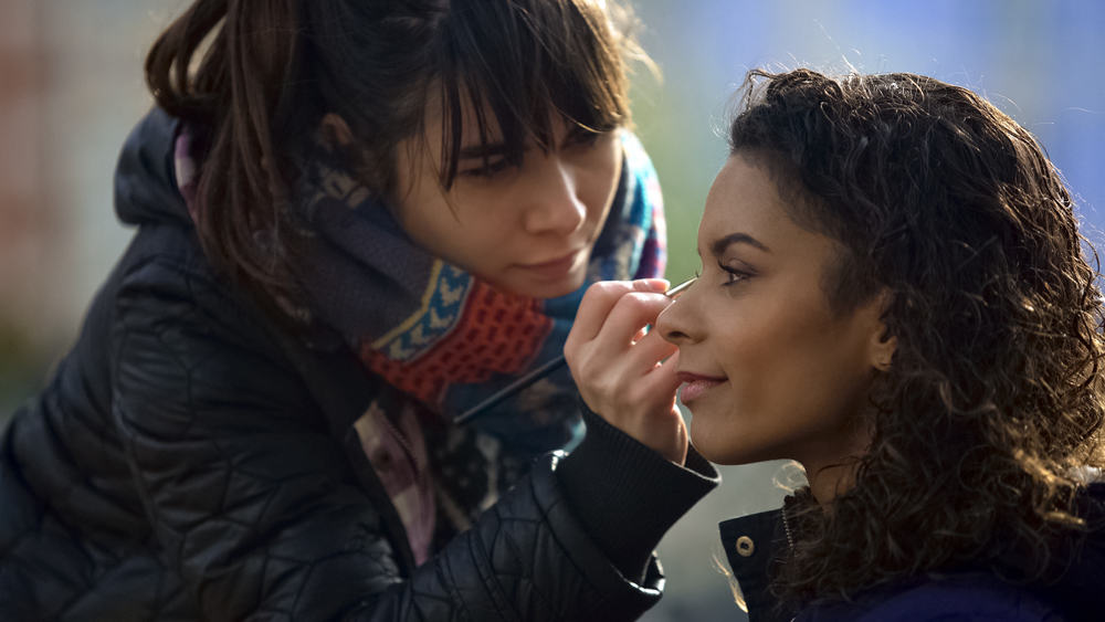 Assistant makeup artist fixing makeup for actress on location