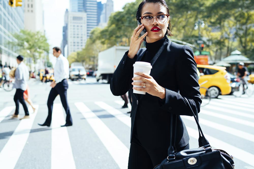 Female executive producer making a deal on her cell phone as she walks through the city