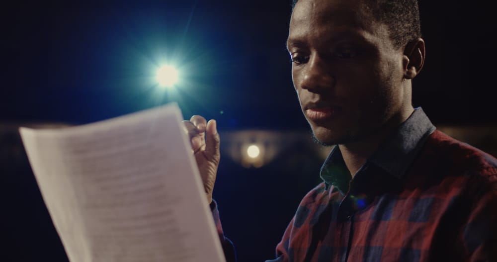 Young black actor reading teleplay on set